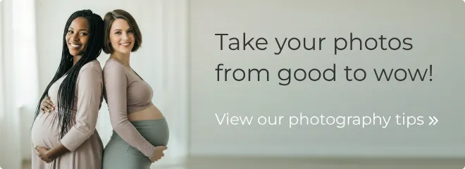 Two smiling pregnant ladies standing back-to-back
